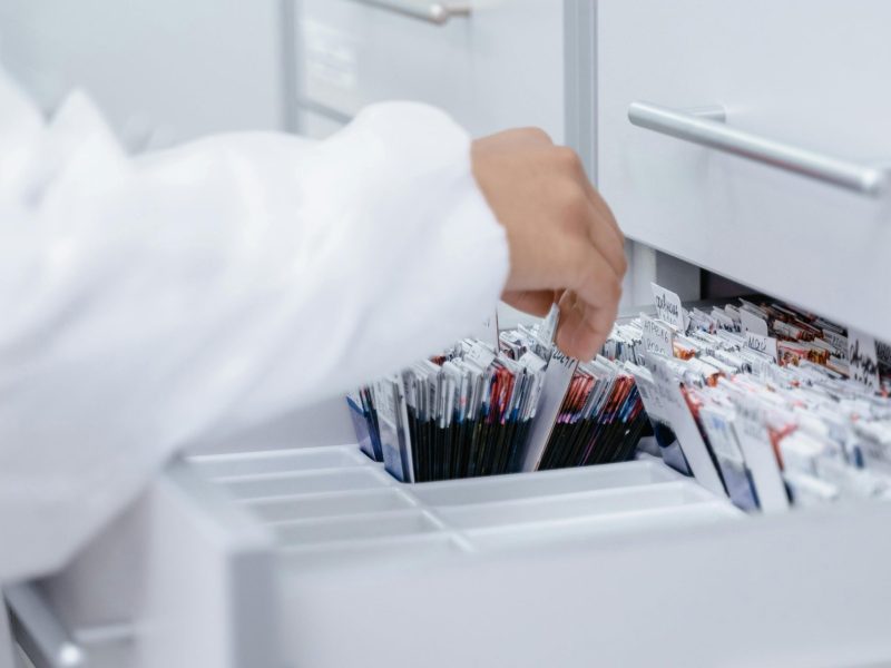 A person wearing a lab coat organizing files in a medical laboratory drawer.